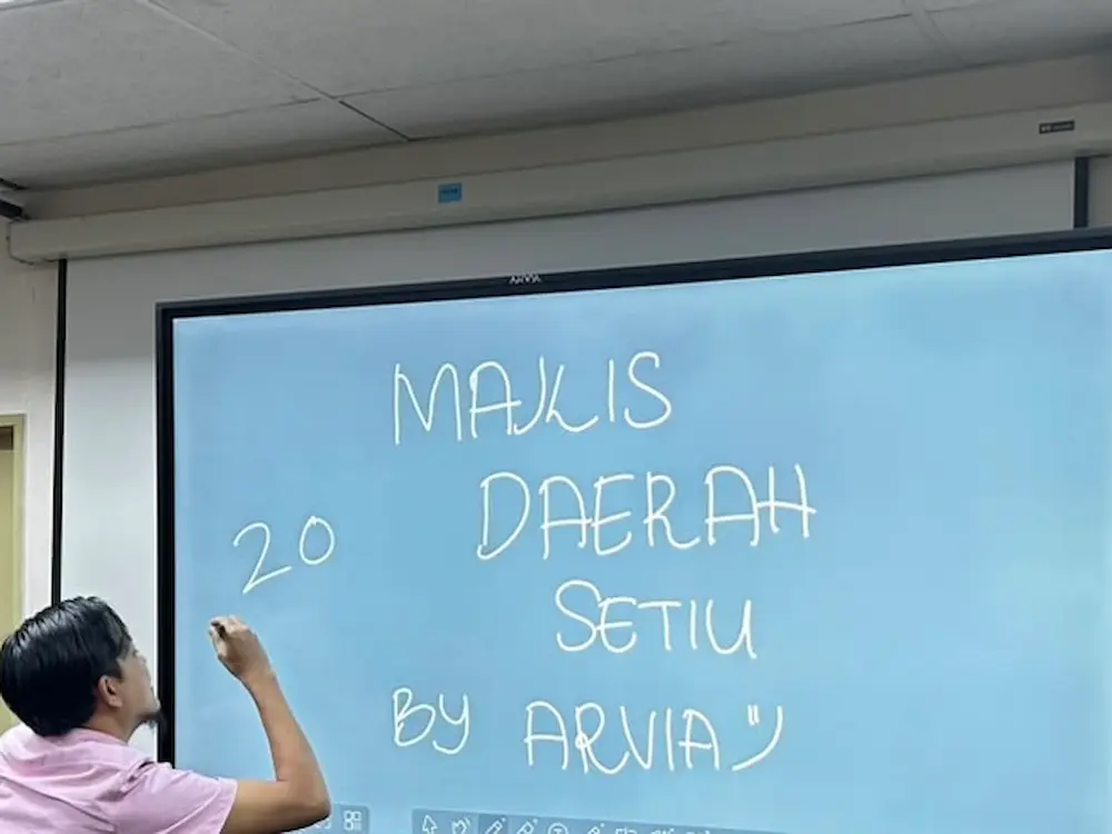 Majlis Daerah Setiu officer annotating directly on the 75-inch smartboard Terengganu display during a meeting