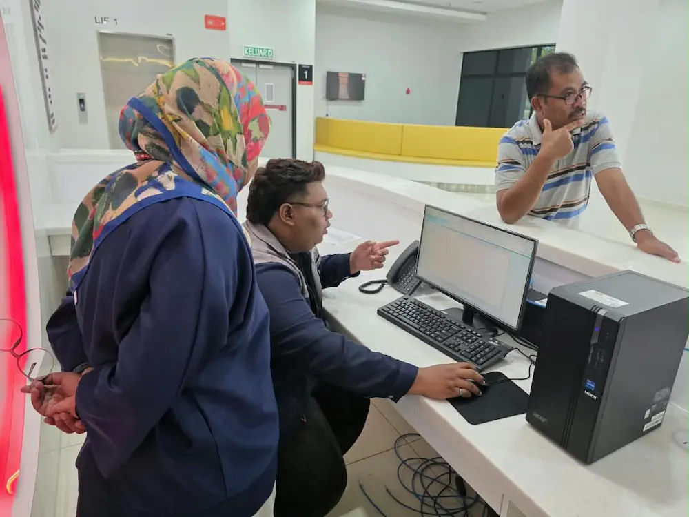Arvia team showing PDWU staff how to use the touchscreen monitor kiosk Kedah display in the lobby